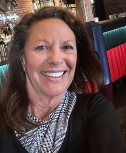 Tracey Devlin Tracey Devlin smiling in casual attire at a modern restaurant, representing professional and friendly customer service in a vibrant dining environment.