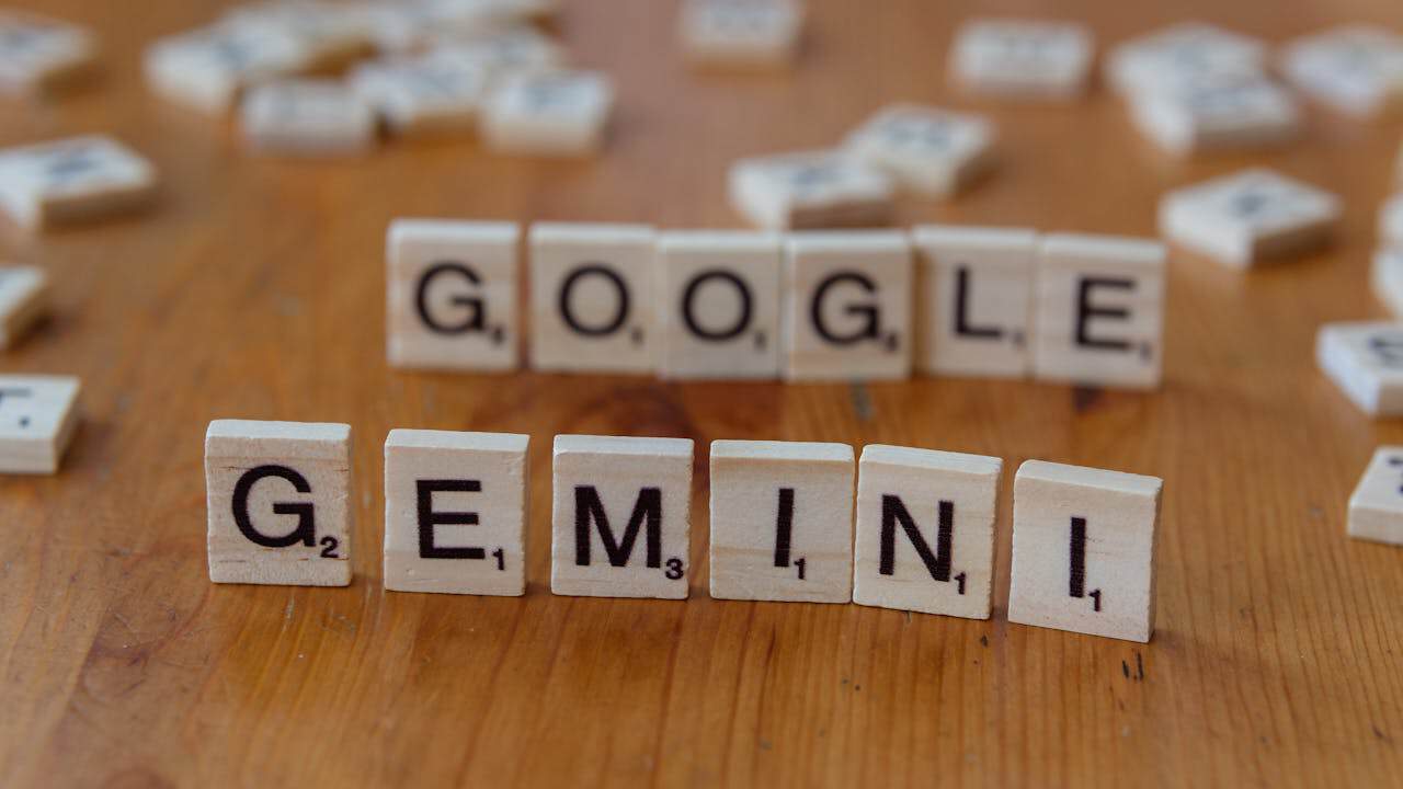 Google Gemini puzzle pieces on wooden surface, spelling out “GEMINI” with scattered tiles in the background.